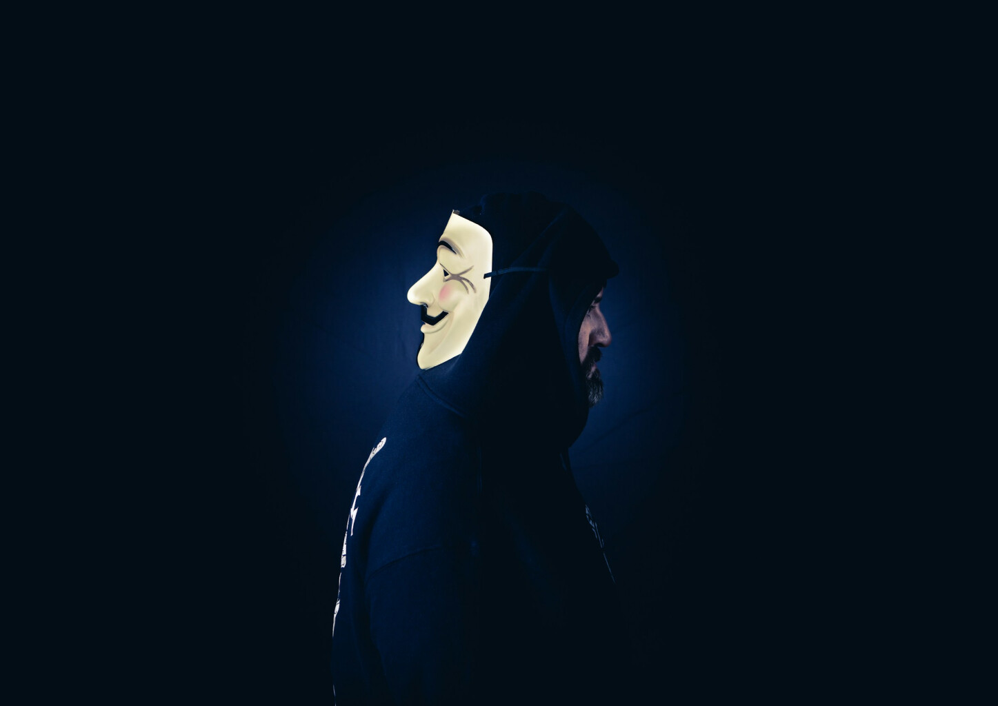 cyber threat actor, wearing guy fawkes mask behind head